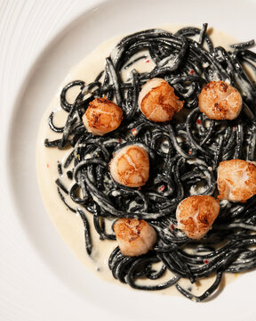 Gourmet black squid ink pasta topped with crispy scallops