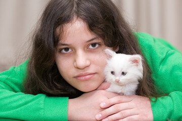 A European girl plays with a white kitten