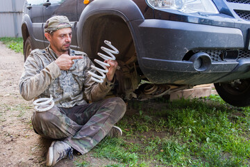 A man holds a broken spring from a car suspension in his hands