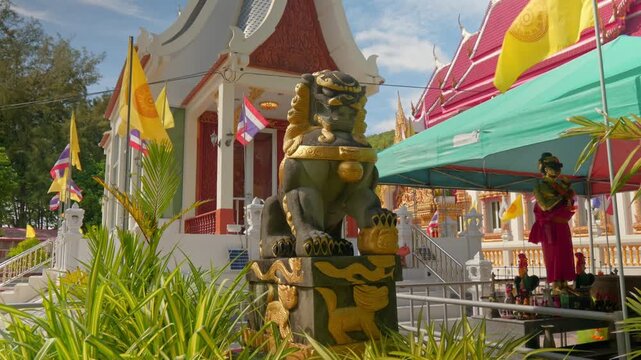 Close-up of a majestic guardian lion statue (Singha) at Wat Nai Harn temple. Features traditional Buddhist architecture and Thai national flags in the background. 4K cinematic travel footage.