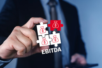EBITDA Financial Metric Concept with Money Puzzle Pieces in Businessman Hand