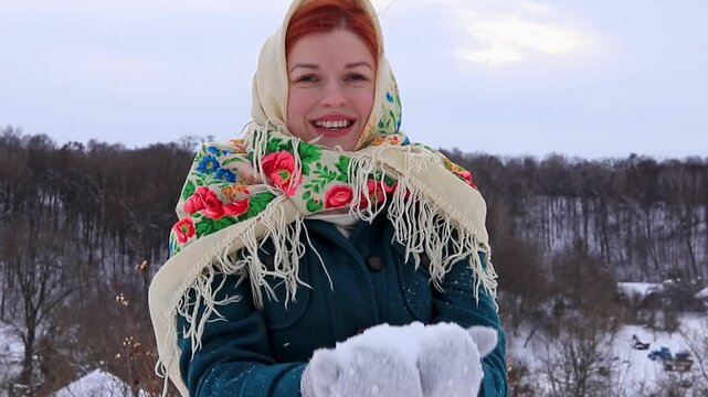 Young woman happily throws snow in the air during a winter walk. Lively emotions, active recreation, cold weather and winter nature.