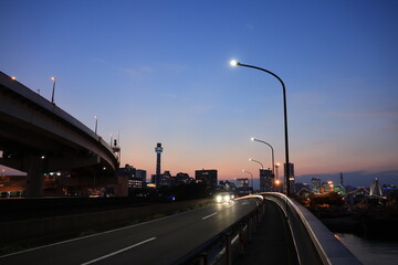 日没直後　オレンジ色に染まる空と横浜の新山下付近の車道とみなとみらいのシルエットと車道