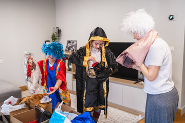 Obraz premium Family members exploring a box of dress up clothes, trying on wigs and costumes for carnival entertainment at home