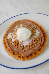 Belgian waffle with chocolate spread, white ice cream scoop and caramel balls