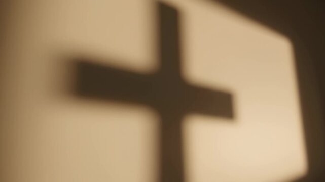 Shadow of cross appears on wall showing light play in quiet setting. Soft lighting creates a calm mood in a personal space. Concept of spirituality, reflection, meditation