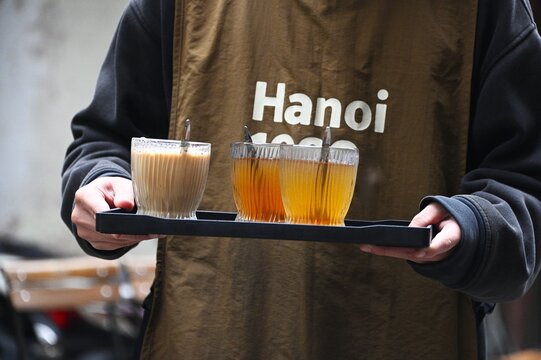 A Server with a Tray of Tea and Coffee Outside a Cafe in Hanoi, Vietnam