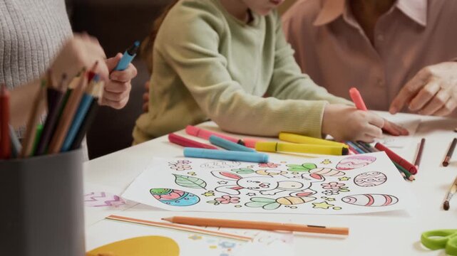 Cropped rack focus shot of unrecognizable little girls enjoying creative activity of coloring Easter patterns with markers and pencils at home