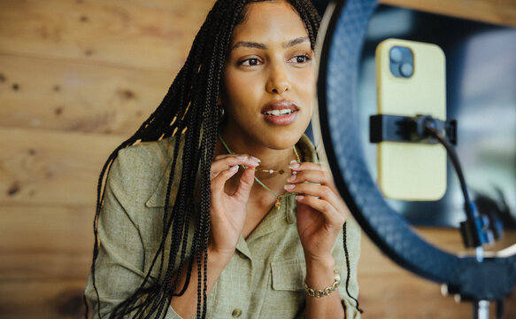 African woman presenting jewelry during live shopping session