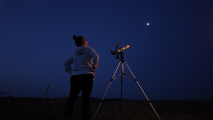 Fototapeta premium Amateur astronomer using telescope for watching stars, Moon, planets and other celestial objects from a field in nature.