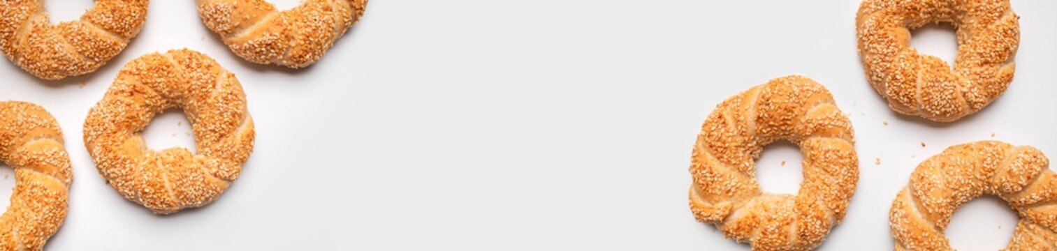 Round bagels with sesame seeds on gray background flat lay top view. Traditional Turkish pastry, simit, crispy fresh bun. Food and bakery background with space for text. Long banner