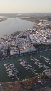 Vertical aerial panoramic view over Ayamonte town, showcasing the riverside waterfront and marina along the Guadiana River in Huelva, Spain.