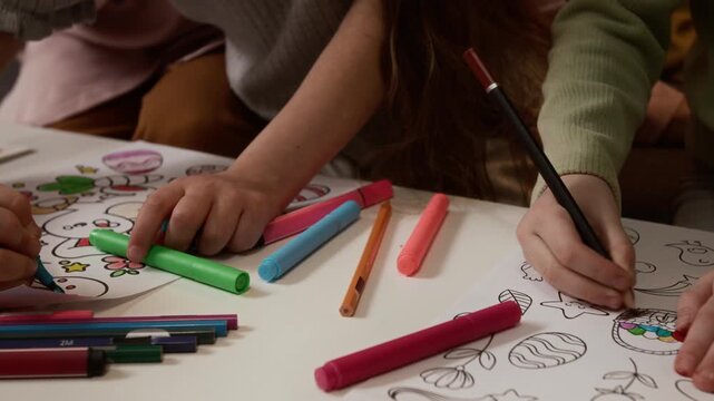 Cropped close up shot of unrecognizable creative children coloring Easter egg drawings using marker and pencil