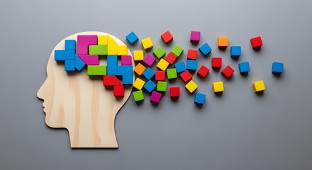 Neurodiversity Celebration  A wooden silhouette of a human head is filled with colorful puzzle pieces, with additional pieces scattered around the head.