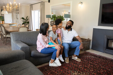 Naklejka premium Diverse family sitting together on gray sofa over patterned red rug in bright living room