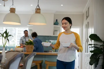 Selbstklebende Fototapeten Zu Kochen Diverse family cooking together at kitchen island carrying white serving bowls, copy space  © wavebreak3