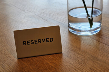 Reserved sign on a wooden table in a restaurant or cafe setting.