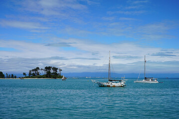 Obraz premium Two boats moored in a harbour in the early morning under a blue sky at Tahuna harbour, Nelson, New Zealand.