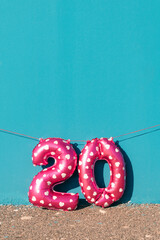 Naklejka premium pink number 20 balloons against a vivid blue wall