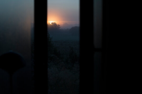 Misty Morning Sunrise Peeking Through Dark Vertical Frame