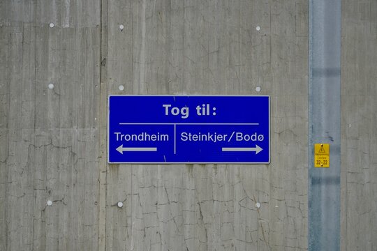Close-up of a blue information sign on a concrete wall at the Vaernes Airport train station in Stjoerdal, Norway.