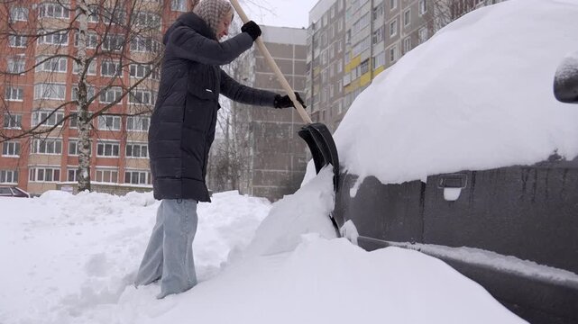 Woman Cleaning Heavy Snow, Woman Removing Deep Snow Assiduously, Woman In Winter Coat Removing Heavy Snow From Car, Woman In Gloves And Coat Cleaning Thick Snow Around Her Car