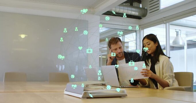 Animation of connected computer icons forming globe over multiracial coworkers discussing in office