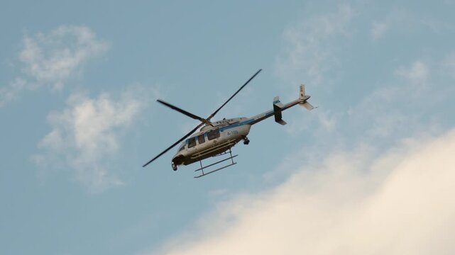 Police Helicopter flying over urban area with rotating blades and blue sky
