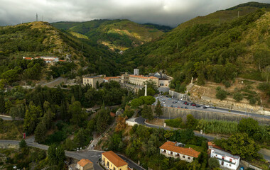 Fototapeta premium Aerial view of the Catholic sanctuary of San Francesco da Paola, in the province of Cosenza, Calabria, Italy. It's a pilgrimage site for Christian faithful, perched among the verdant hills. Cloudy day