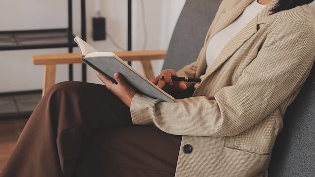 Elearning. Close up of smiling young female remote student watch training lecture on laptop pc take notes at paper workbook by hand. Millennial lady get distant education write thesis of online lesson