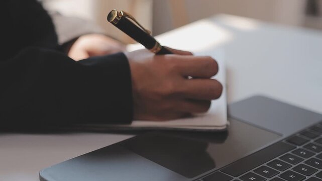 Elearning. Close up of smiling young female remote student watch training lecture on laptop pc take notes at paper workbook by hand. Millennial lady get distant education write thesis of online lesson