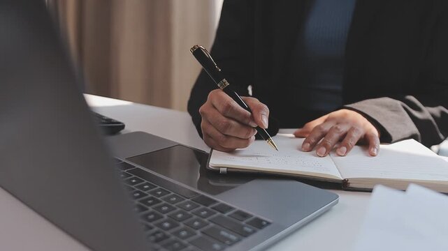 Elearning. Close up of smiling young female remote student watch training lecture on laptop pc take notes at paper workbook by hand. Millennial lady get distant education write thesis of online lesson