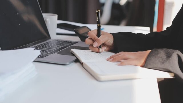 Elearning. Close up of smiling young female remote student watch training lecture on laptop pc take notes at paper workbook by hand. Millennial lady get distant education write thesis of online lesson