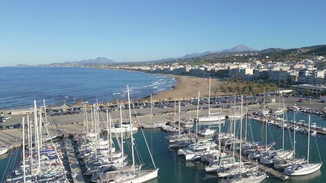 Aerial view of Rethymno marina in Crete with luxury yachts and fishing boats moored in the turquoise mediterranean sea along the historic coast
