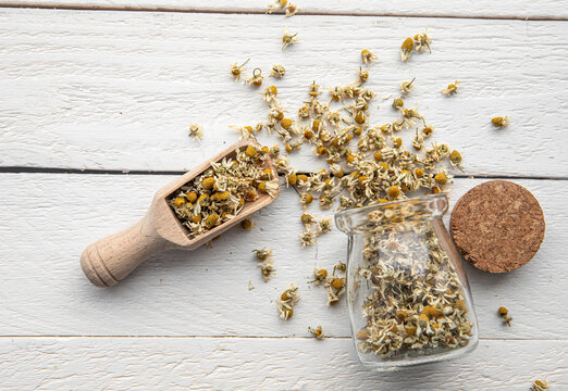 Matricaria chamomilla, commonly known as chamomile, wild chamomile, or scented mayweed. Organic dried herbal tea powder made from flower blossoms. Tea ground in a glass jar on a wood board background.