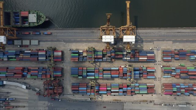A dynamic aerial time-lapse of a bustling port, where cranes load massive container ships under a dramatic, time-compressed sky.


