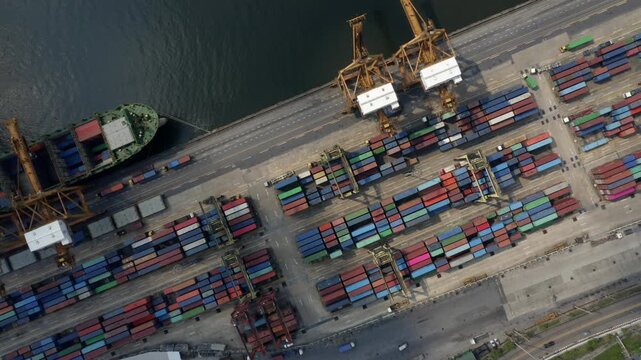 A dynamic aerial time-lapse of a bustling port, where cranes load massive container ships under a dramatic, time-compressed sky.

