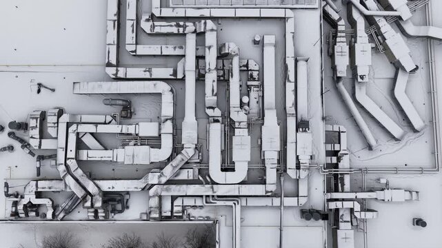 Aerial close-up of an industrial rooftop in Vilnius, Lithuania, showing a dense network of HVAC ducts and ventilation systems partially covered in snow.