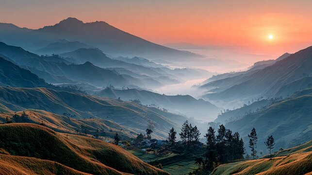 A scenic panorama of mountainous terrain during a vibrant sunrise, with layers of fog and light. A village nestles among hills