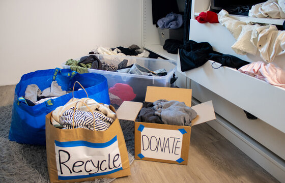 Two paper bags full with clothes for recycling and donation standing on the floor of a wardrobe 