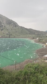 Vertical video of strong wind and waves on Lake Kournas, winter windy weather in Crete, Greek nature landscape.