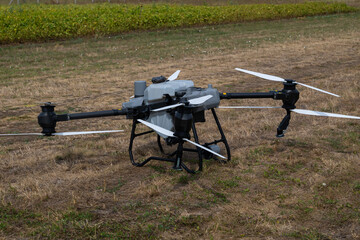 Industrial agricultural drone with multiple rotors resting on a dry field for aerial surveying and crop monitoring