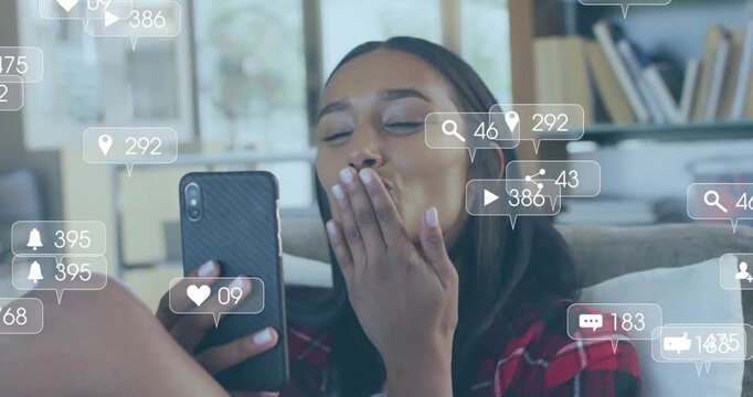 Animation of media icons over woman using smartphone on couch