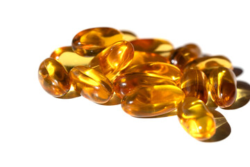 Shiny golden vitamin D capsules piled on white background, selective focus highlights glossy texture promoting vitamins, woman health and modern lifestyle wellness.