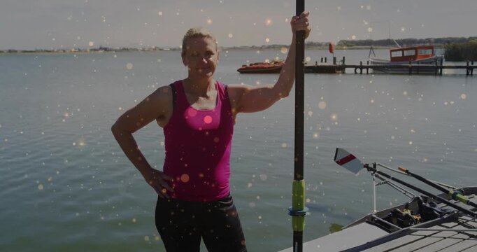 woman holding rowing oar on wooden dock by lake, showing animated fitness chart overlay