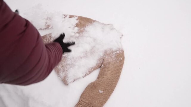 Giving a hand-knit wool garment a snow bath &mdash; a traditional way to clean natural knitted clothes. 100% wool sweater lay on snow covered with snow for cleaning.