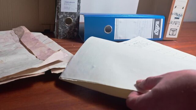 Accountant at office desk looking through old ledger document files