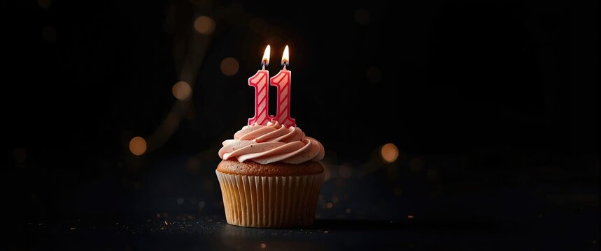 Cupcake with a birthday candle numbered 111 against a blurred black background and gentle lights