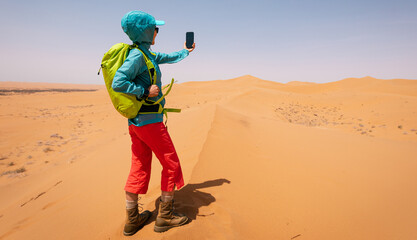 Woman backpacker taking photo with smart phone in the desert © lzf