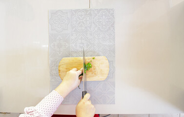 Chef hands slicing fresh green chili on wooden cutting board